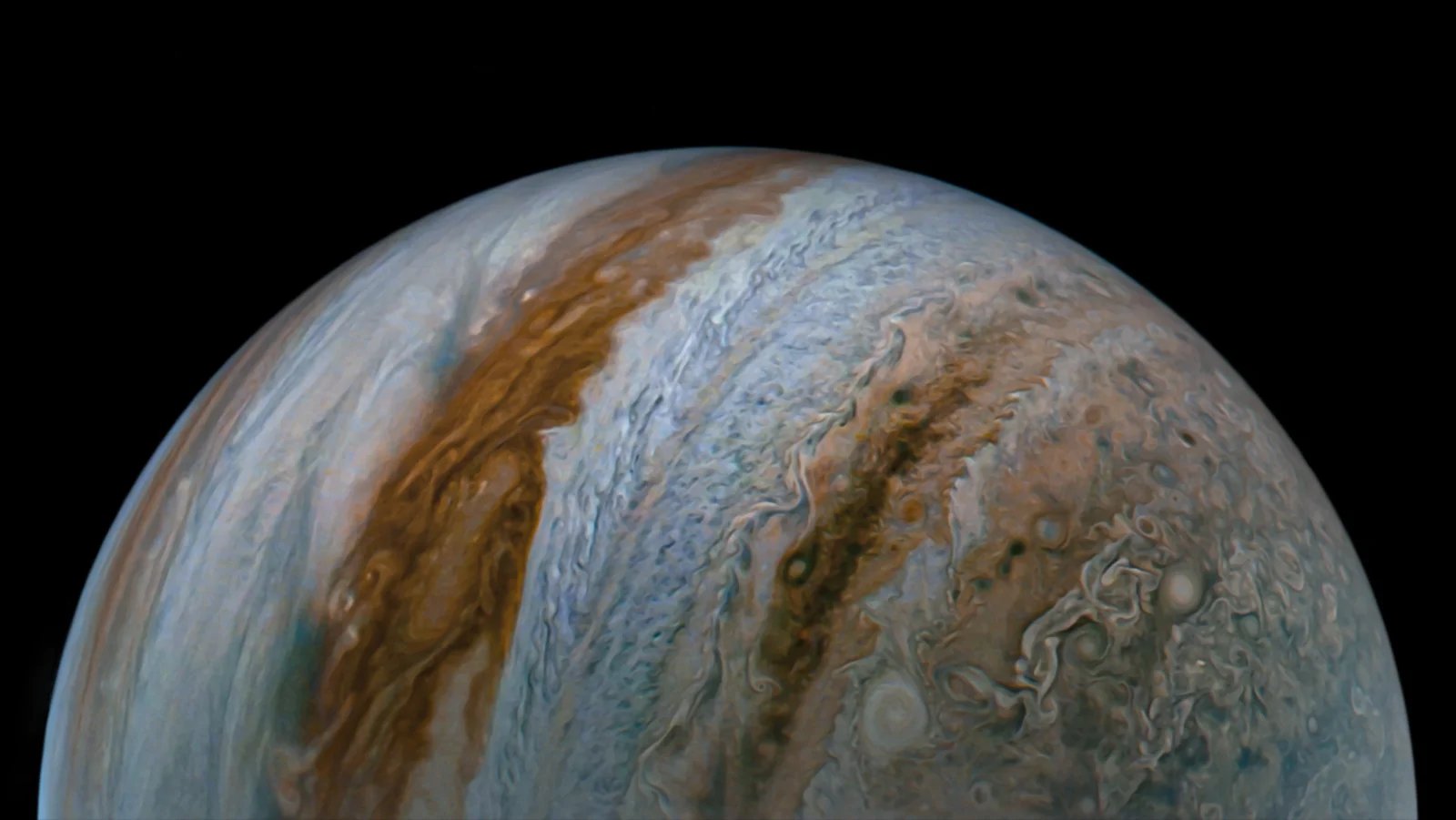 A close up of the planet Jupiter in space its various orange and brown atmospheric layers curving almost vertically